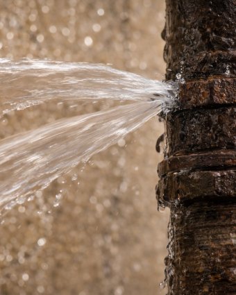 Plumber repairing pipes under a kitchen sink using tools